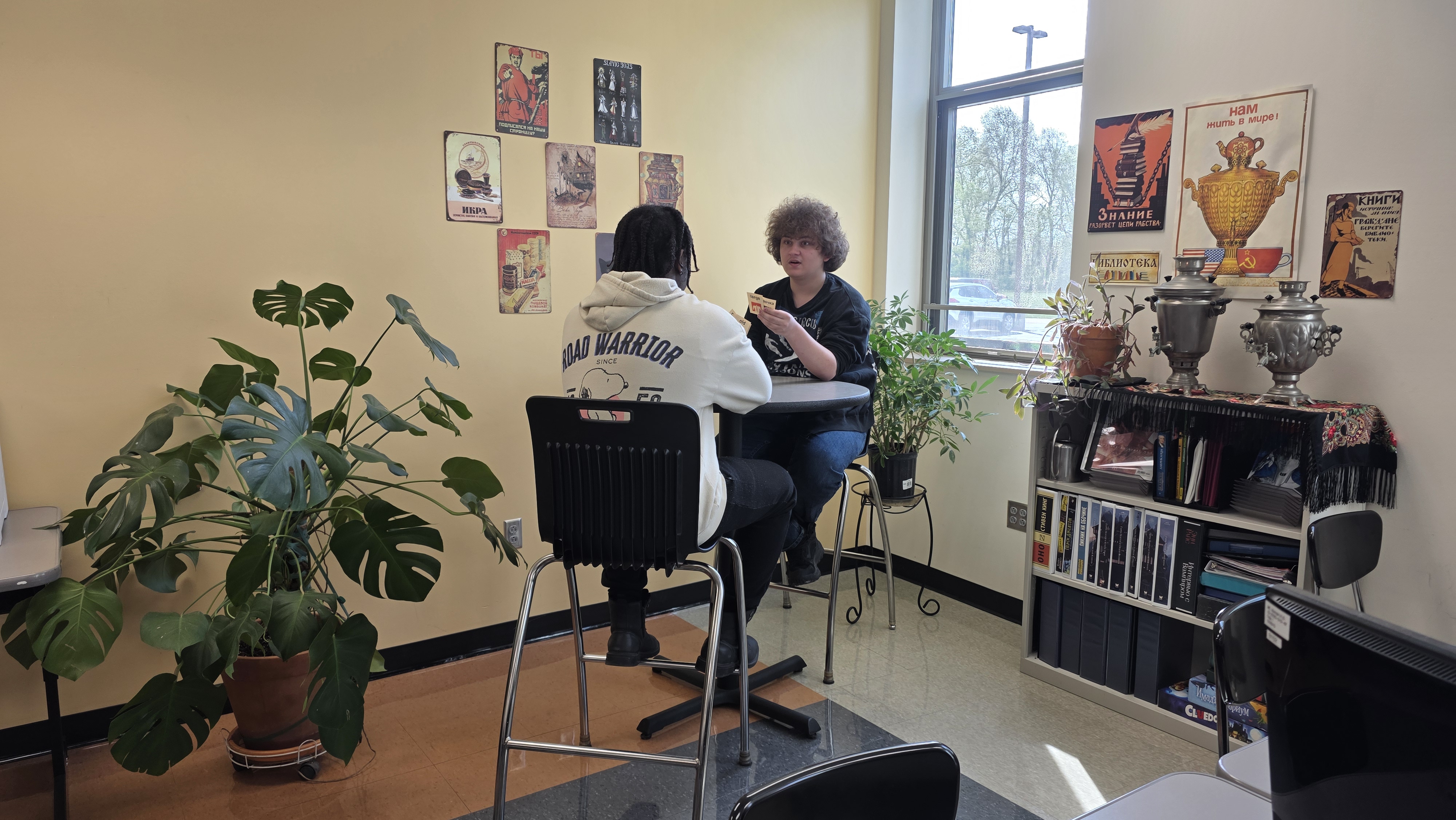 Two students reviewing flashcards in a corner seating arrangement near a window in a classroom
